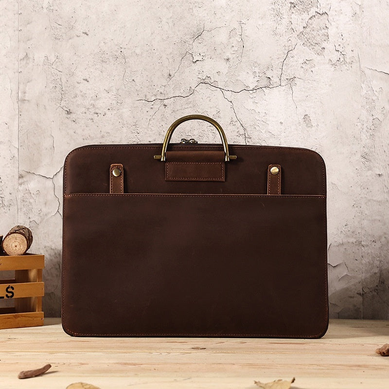 Brown Crazy Horse leather men's business handbag with brass handle and front pocket on wooden surface