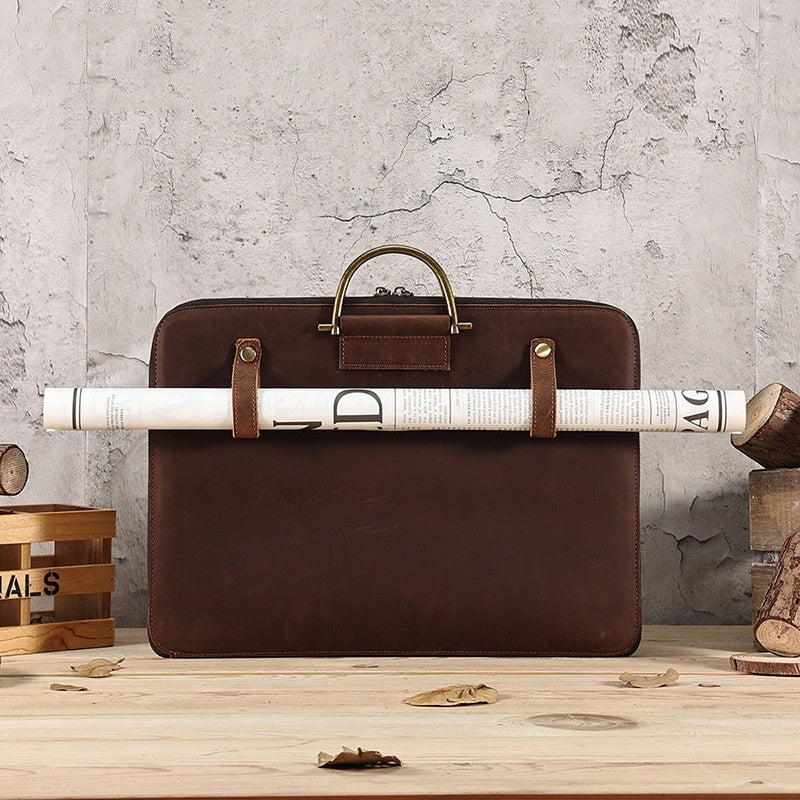 Brown Crazy Horse leather men's business handbag with rolled document holder and brass handle on a wooden surface.