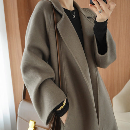 Women's mid-length reversible cashmere coat in a loose over-knee design, styled with a brown shoulder bag and black inner layer