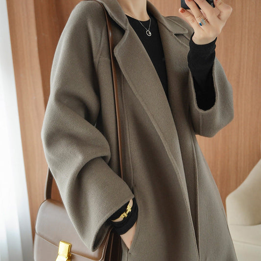 Women's mid-length reversible cashmere coat in a loose over-knee design, styled with a brown shoulder bag and black inner layer
