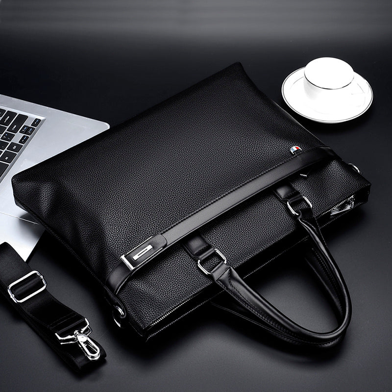 Black large capacity business handbag men's soft leather briefcase with handles and detachable shoulder strap next to laptop and cup