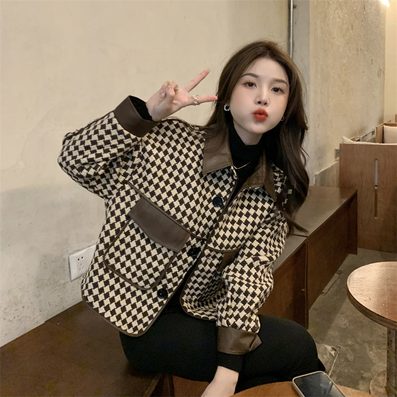 Woman wearing a Chanel Coat Women's checkered wool-cashmere blend jacket with leather collar and cuffs sitting indoors making a peace sign.