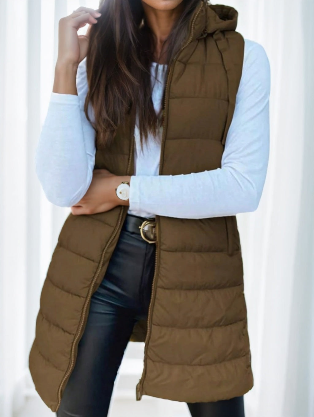Woman wearing brown elegant hooded puffer vest over white long-sleeve shirt and black pants